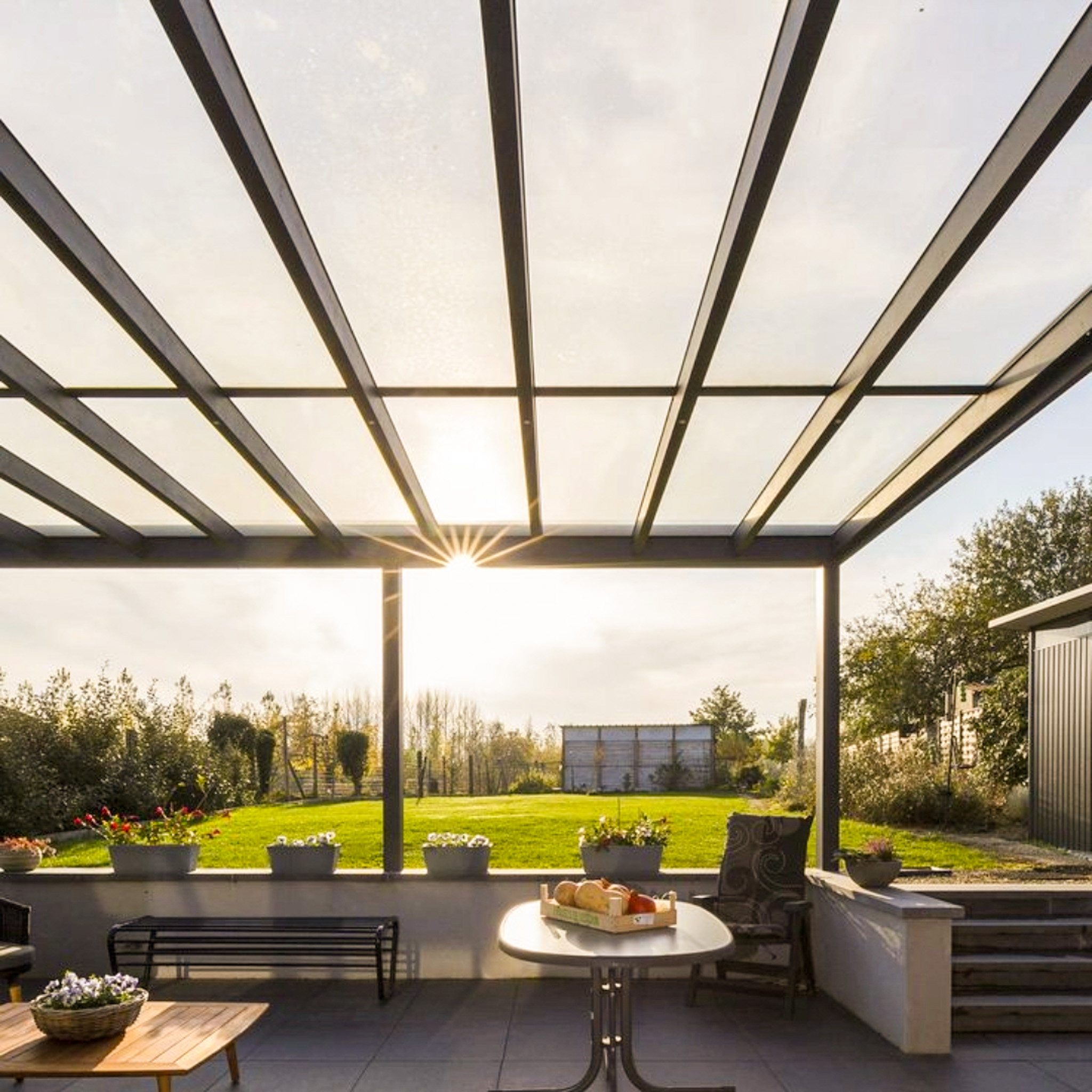 Vue vers le haut d'une pergola avec le soleil brillant à travers sa structure de toit en verre