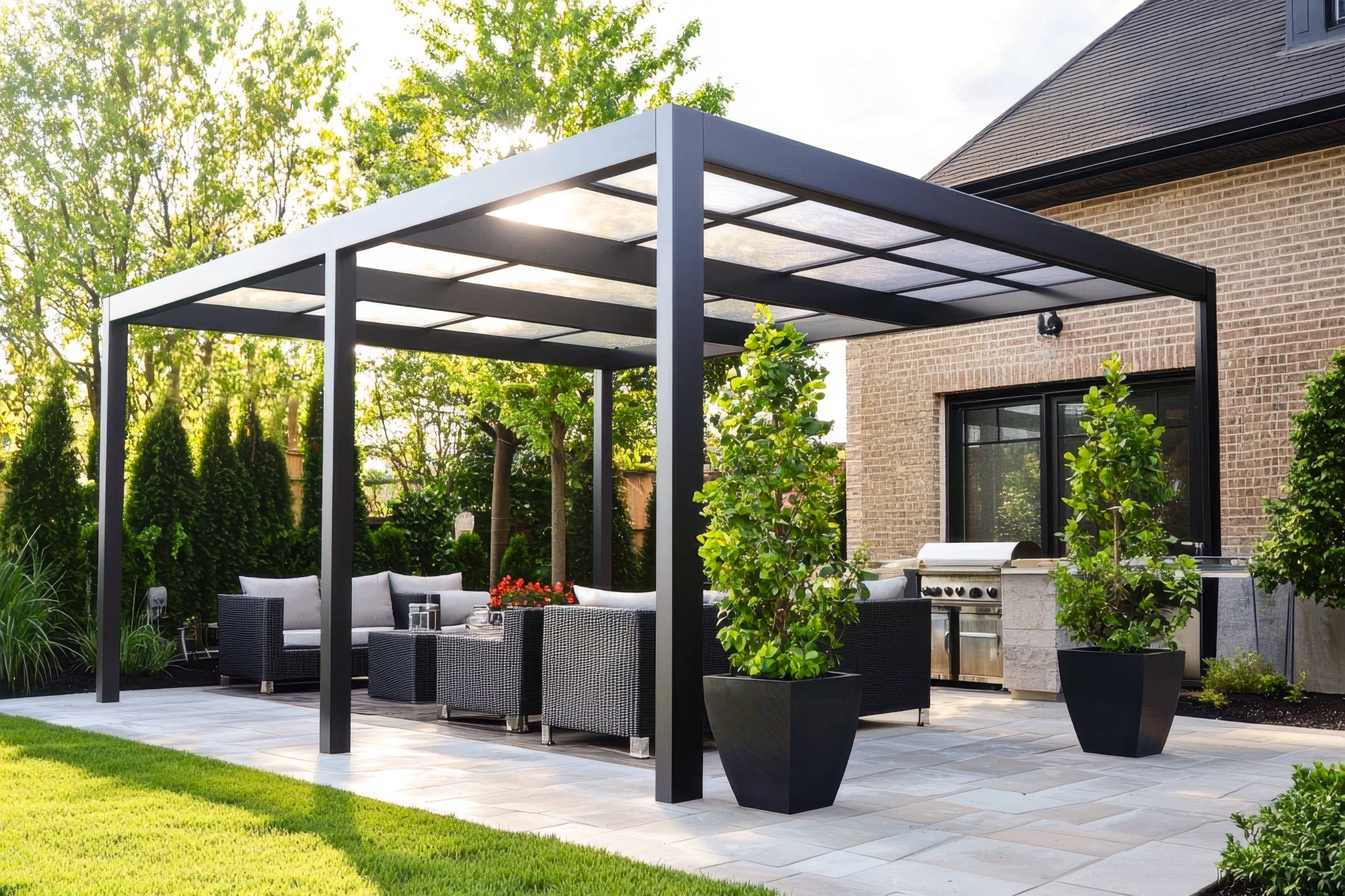 Pergola bioclimatique de luxe avec parois vitrées abritant un salon d'angle moderne et un espace repas donnant sur un grand jardin.